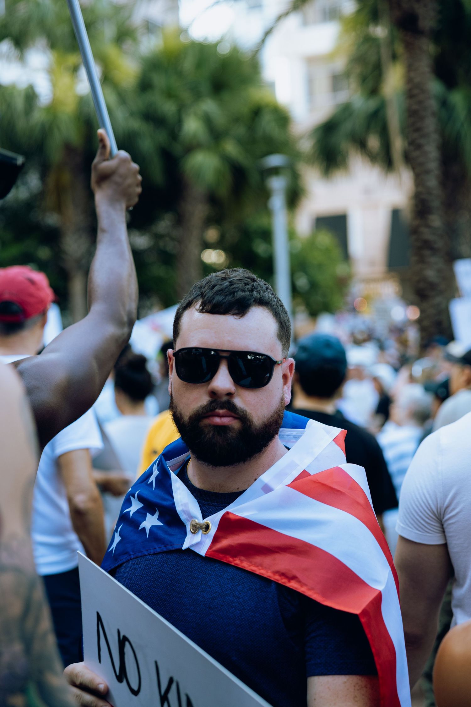 Protestor wearing sunglasses and American flag attire at a public demonstration.