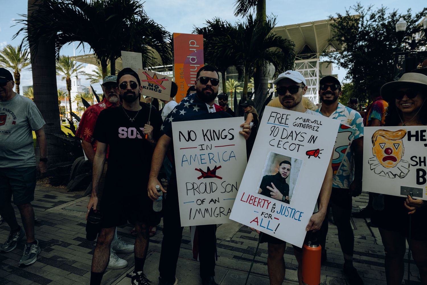 Protesters hold signs at a rally with messages advocating for solidarity and social justice.