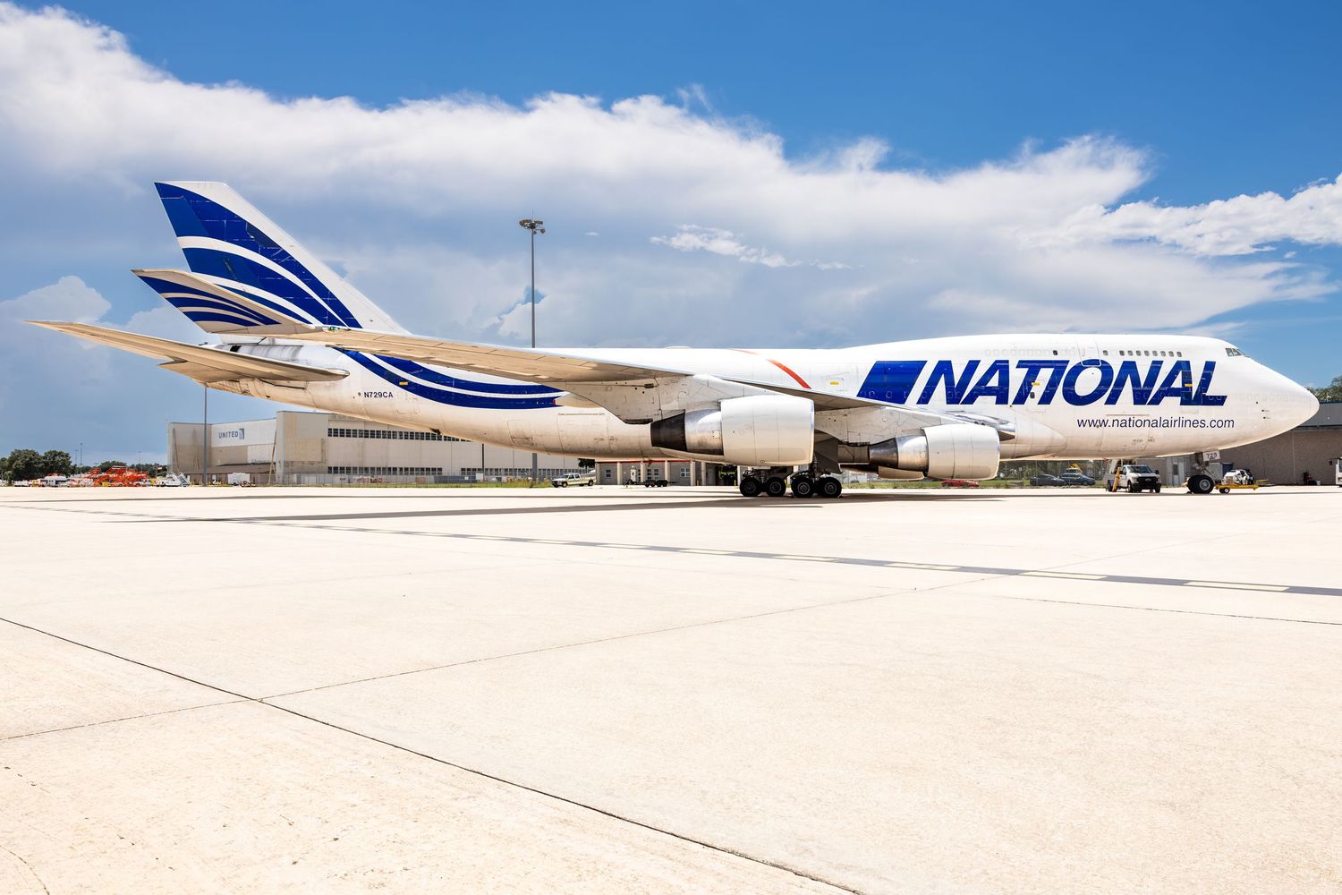 National Airlines Boeing 747 cargo aircraft parked on tarmac under blue sky with white and blue livery.