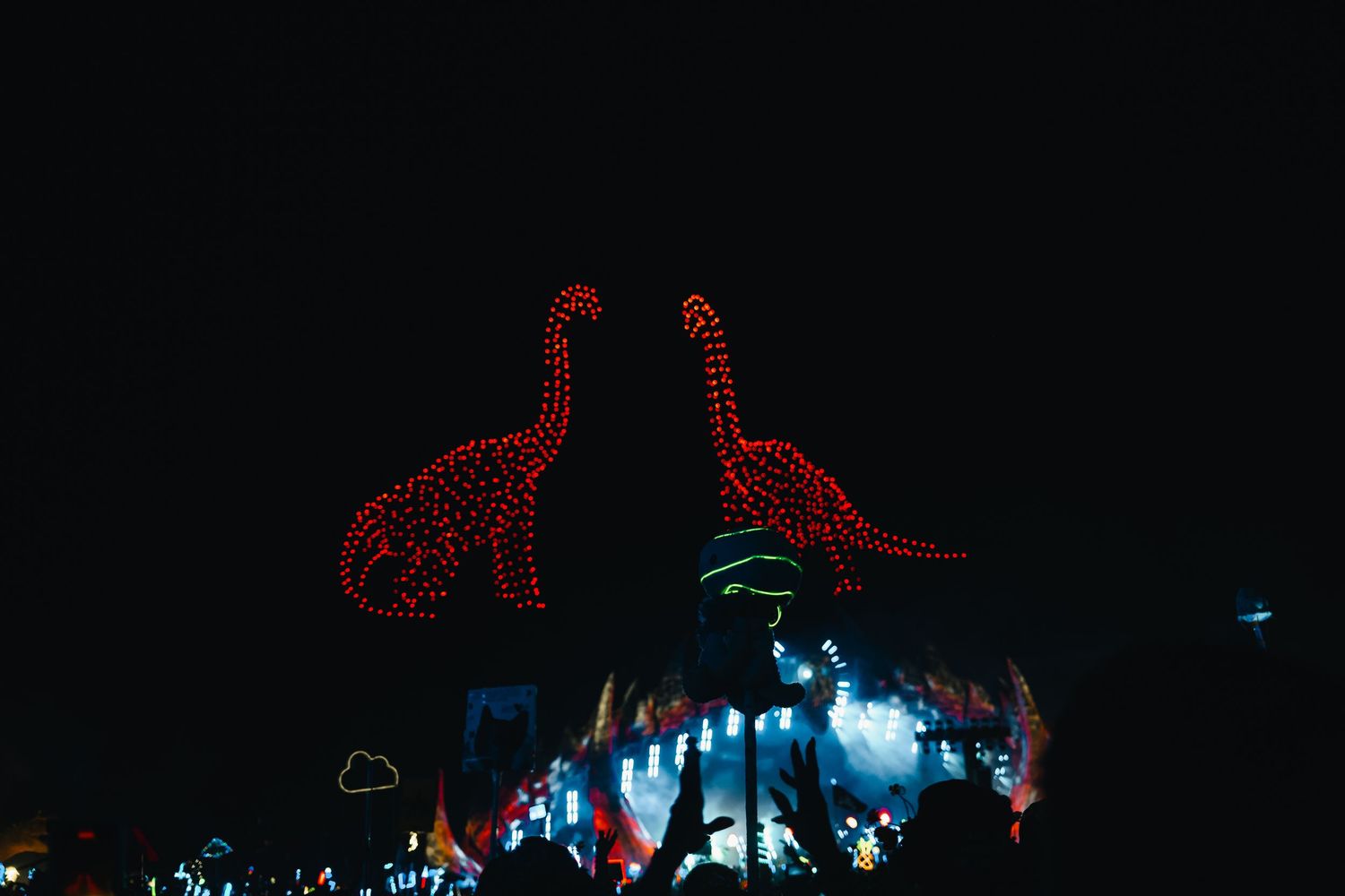 Red neon dinosaur lights illuminate a dark city street at night creating a whimsical urban scene.