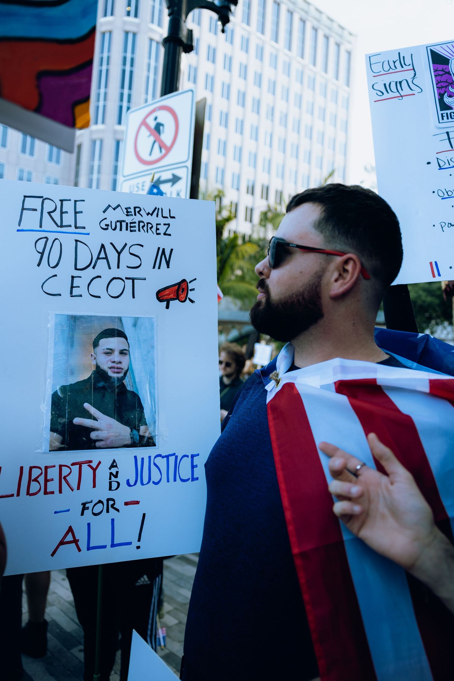 Protesters hold signs demanding liberty and justice at a civil rights demonstration in an urban setting.