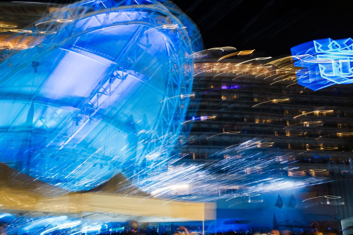 Long exposure photography creates blue light trails against dark background with streaking motion effects.