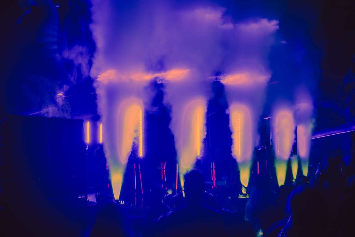 Illuminated fountains create a dramatic display with blue and yellow lights against the dark night sky.