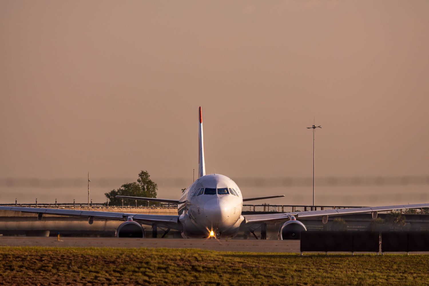 Commercial airplane taxiing on runway at sunset with warm golden sky in background at international airport.