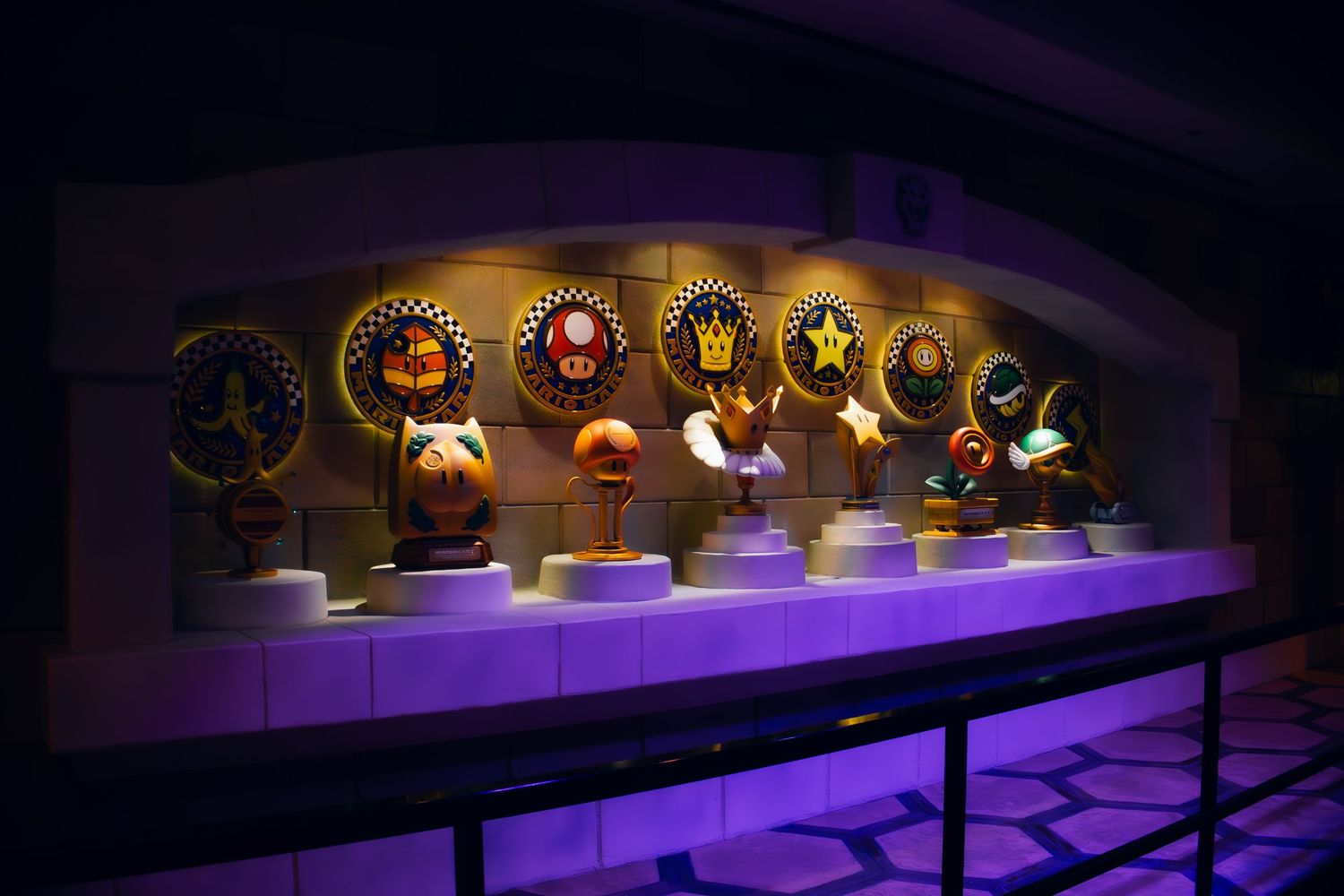 A row of illuminated Grammy Award trophies displayed on a purple-lit shelf against a dark background.