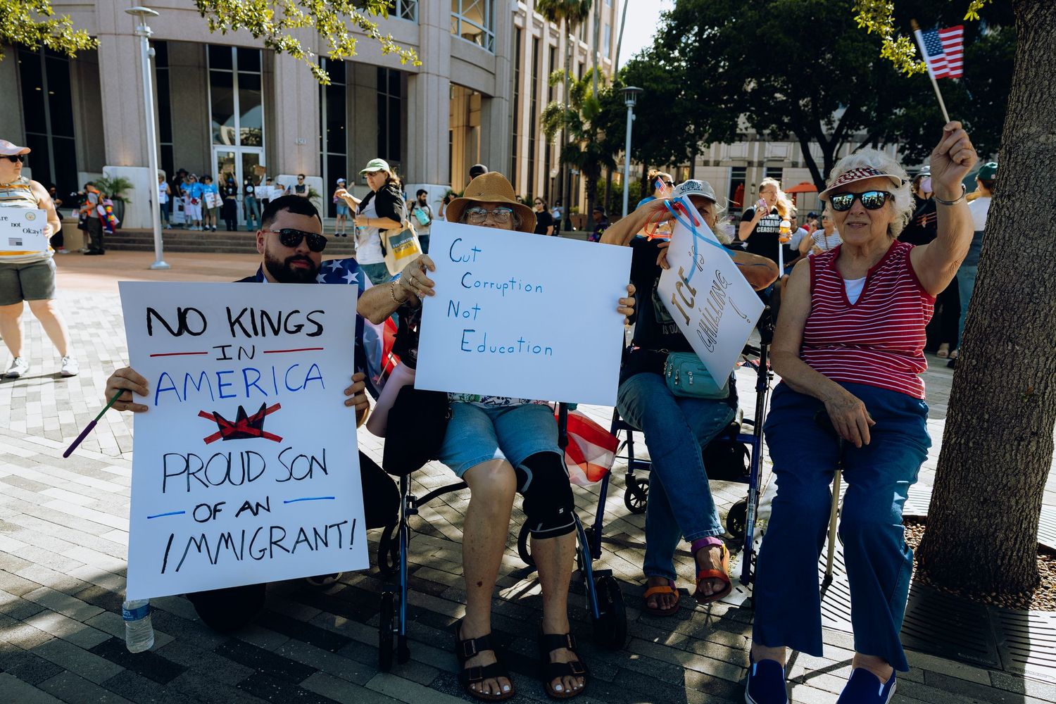 Protesters hold signs at a demonstration against immigration policies on a city street.