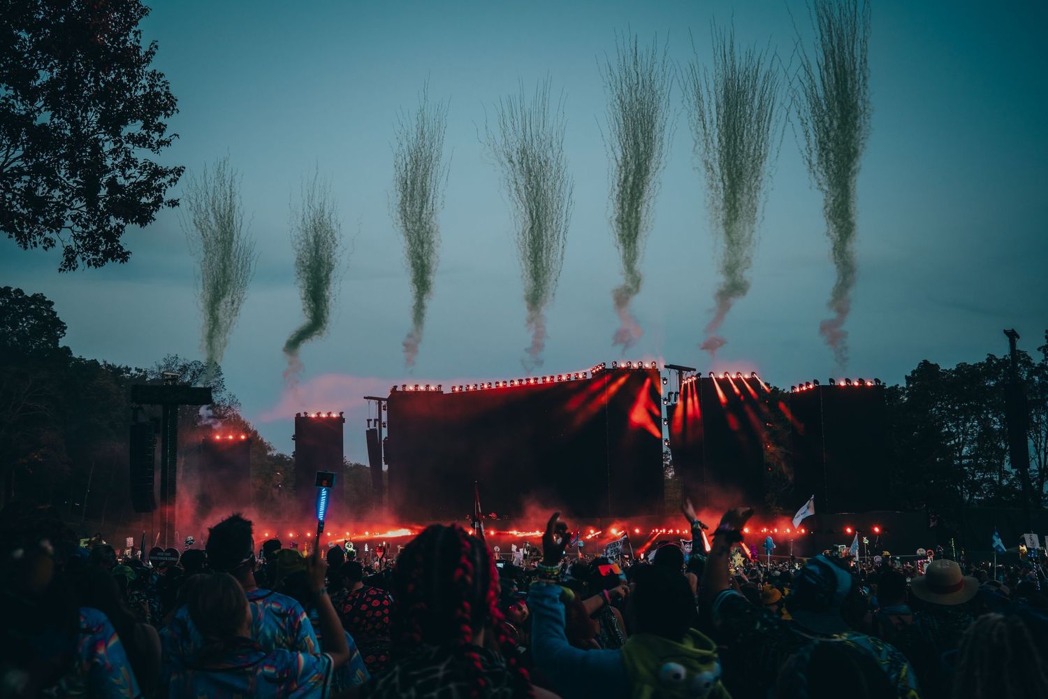 A series of outdoor concert photos showing silhouettes of trees against a red-lit stage and crowd at dusk.