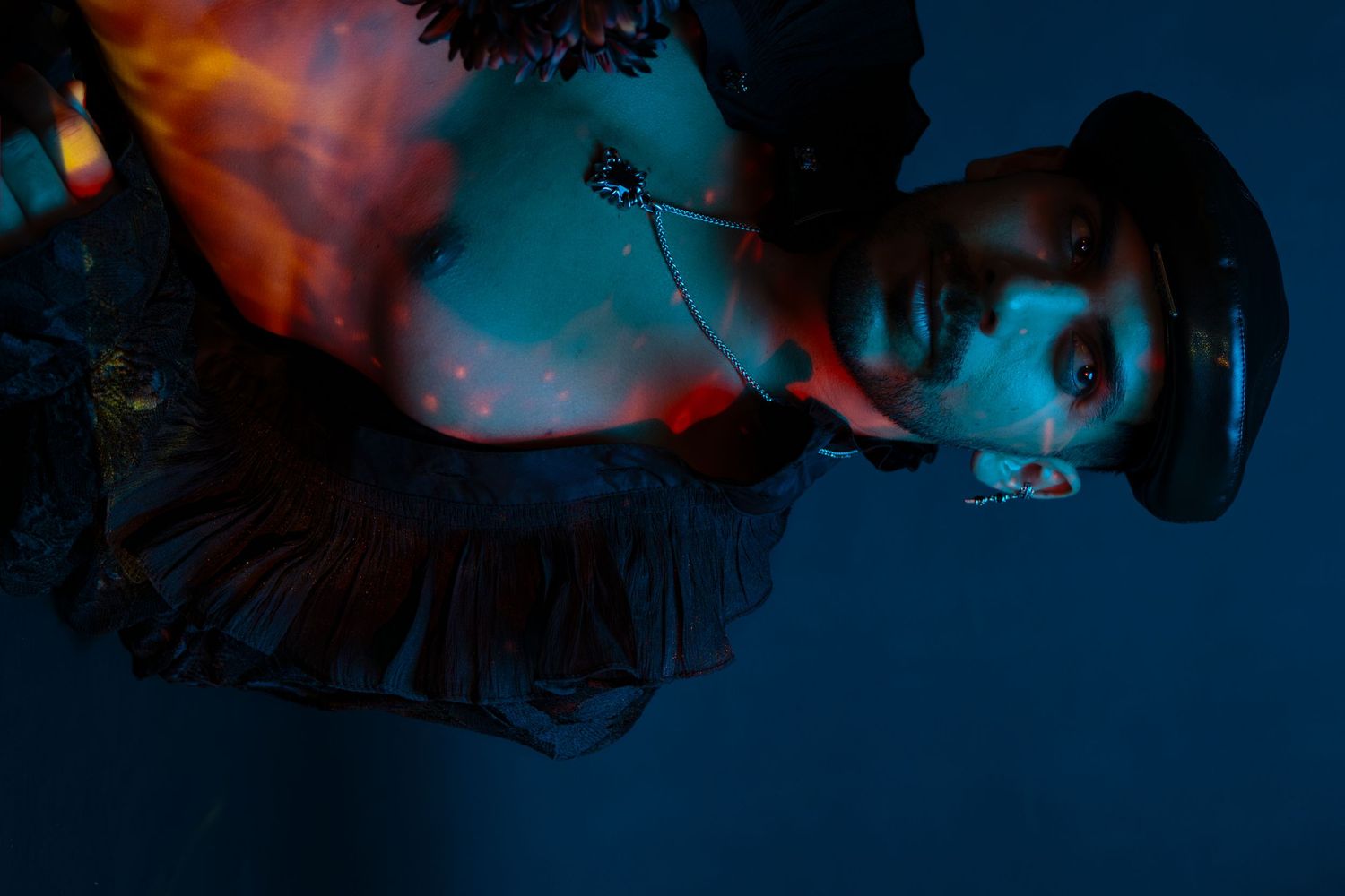 A dark silhouette of a person against a deep blue and orange sky with lens flare effects.