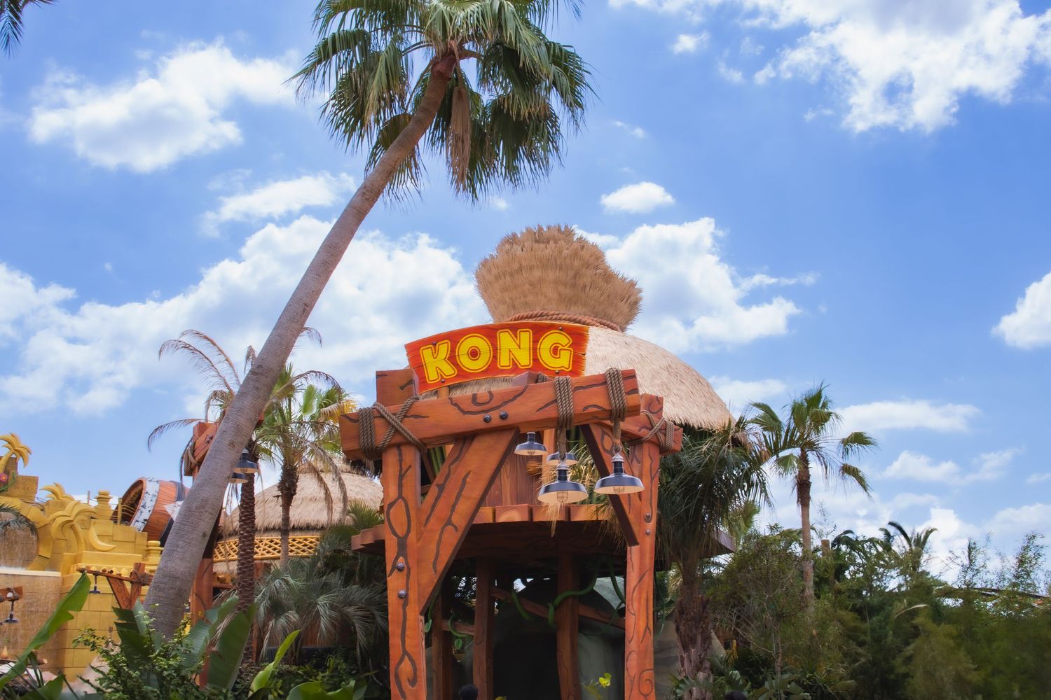 Entrance sign to Kong attraction at Universal Studios theme park with palm trees and blue sky overhead.
