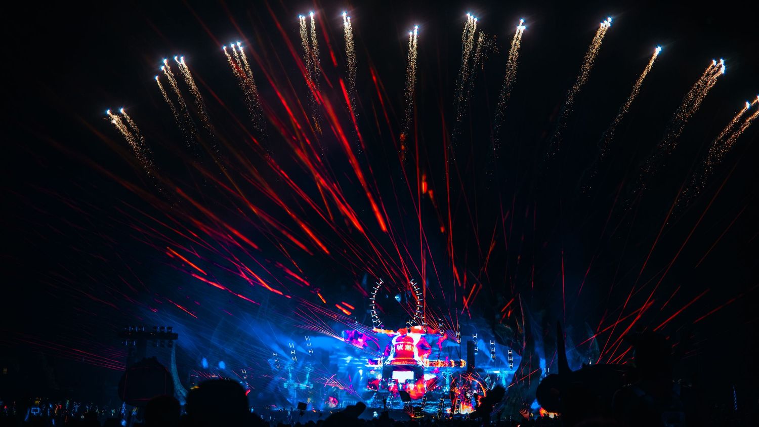 Concert stage illuminated with dramatic red and blue laser light beams creating a spectacular visual display during performance.