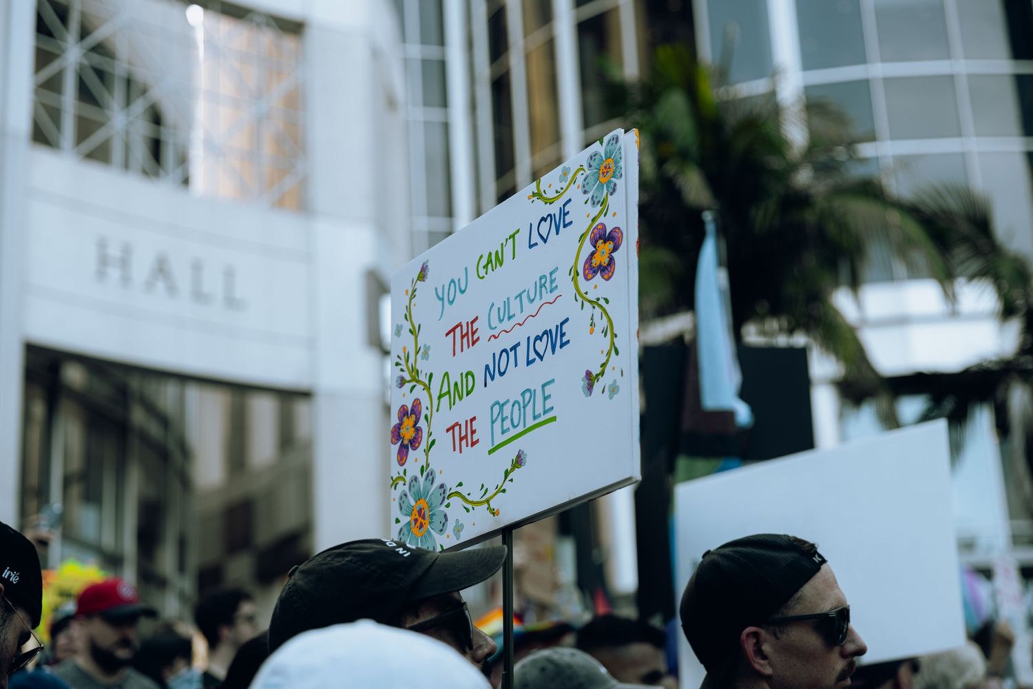 Colorful protest sign held up against city building backdrop.