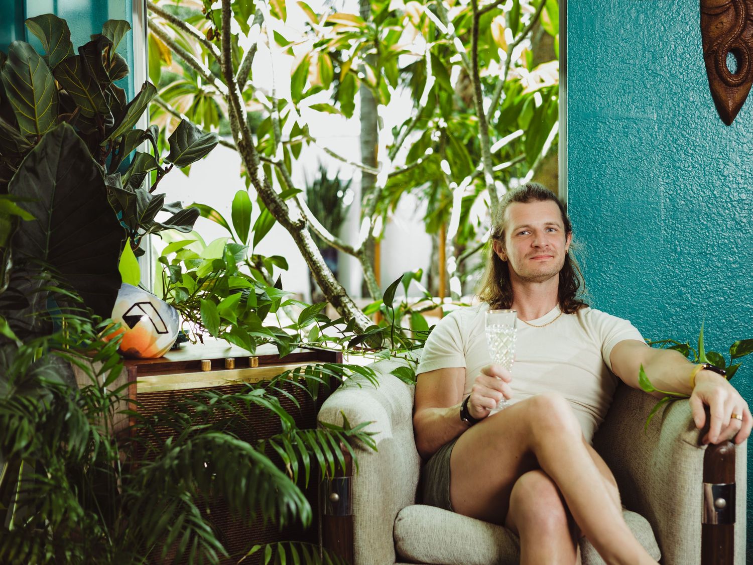 A series of photos showing someone sitting on a porch with lush green plants and a turquoise wall in the background.