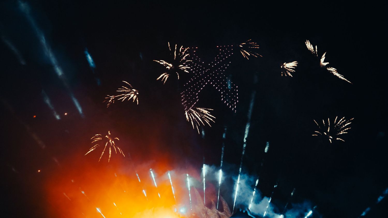 Vibrant fireworks display illuminates the night sky with bursts of colorful pyrotechnics against a dark background.