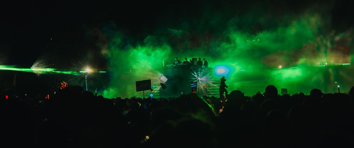 Stunning green aurora borealis lights dance across the night sky above silhouetted trees and buildings.