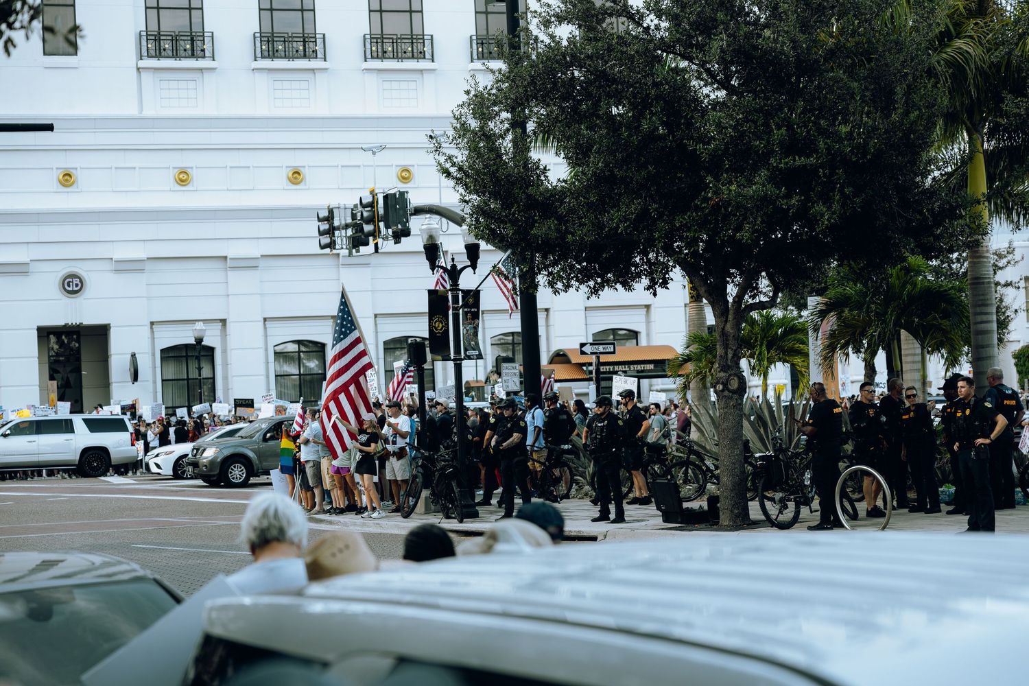 Police and protesters gathered on city street with American flags visible.