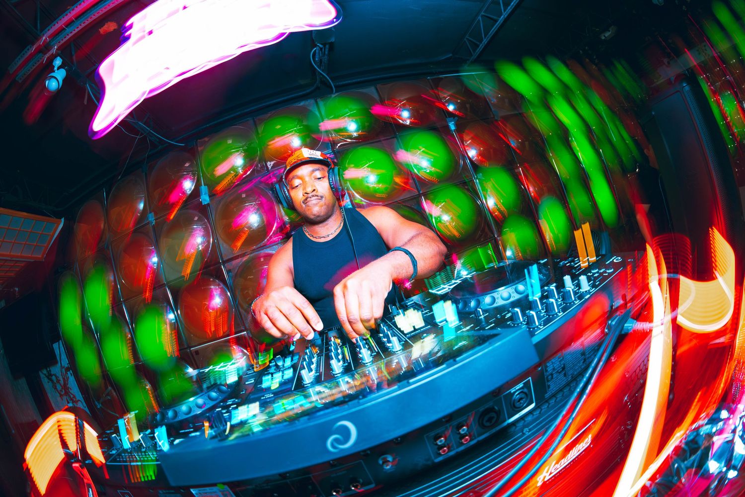 DJ performing at a vibrant nightclub with colorful lights and fish-eye lens effect.