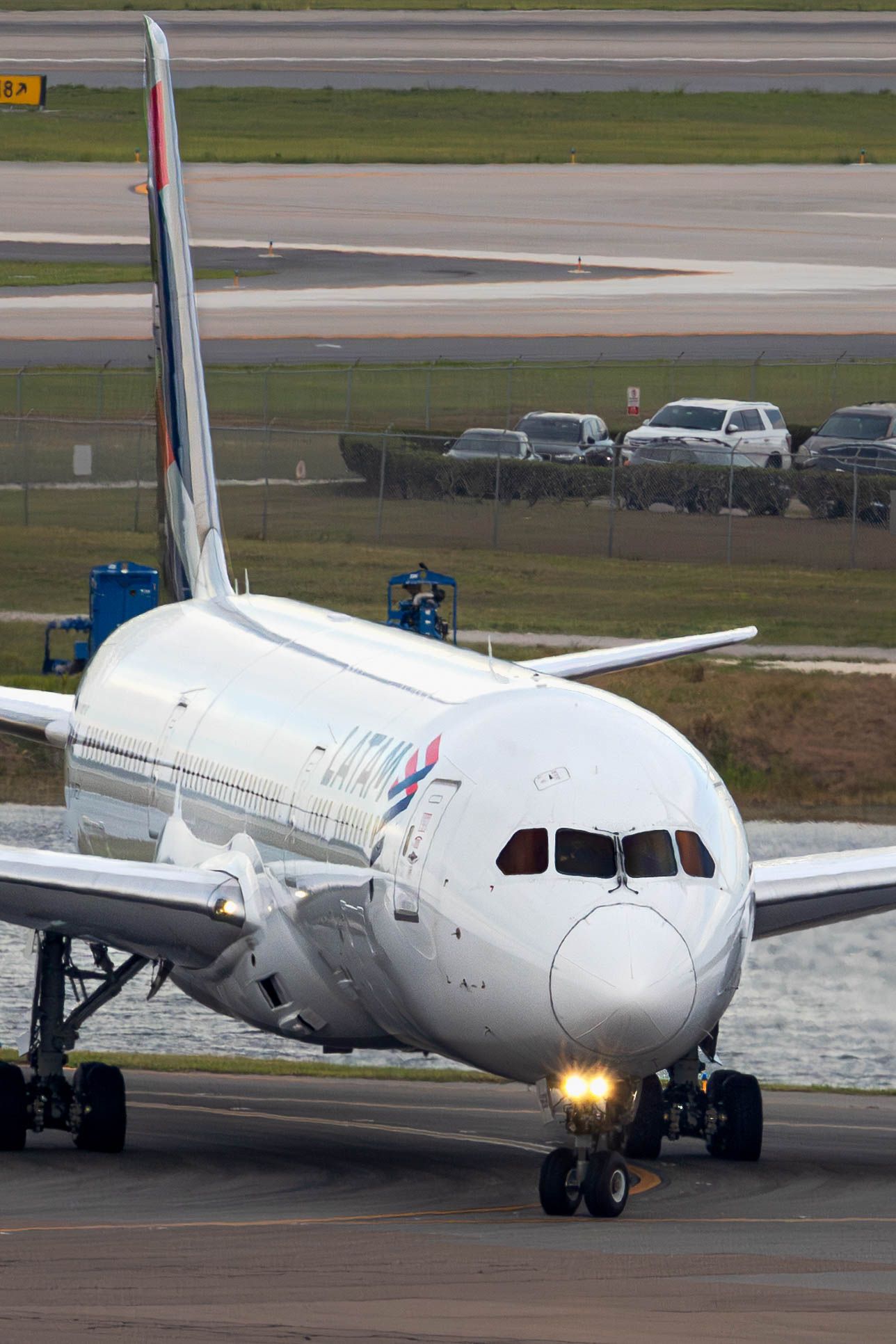 LATAM Airlines Boeing 787 Dreamliner taxiing on airport runway with landing lights on.
