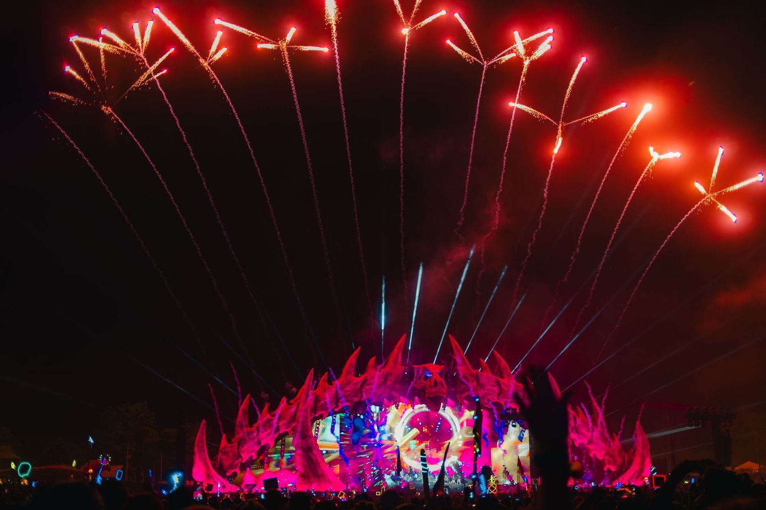 Vibrant red fireworks illuminate the night sky during a spectacular pyrotechnic display at an outdoor event.