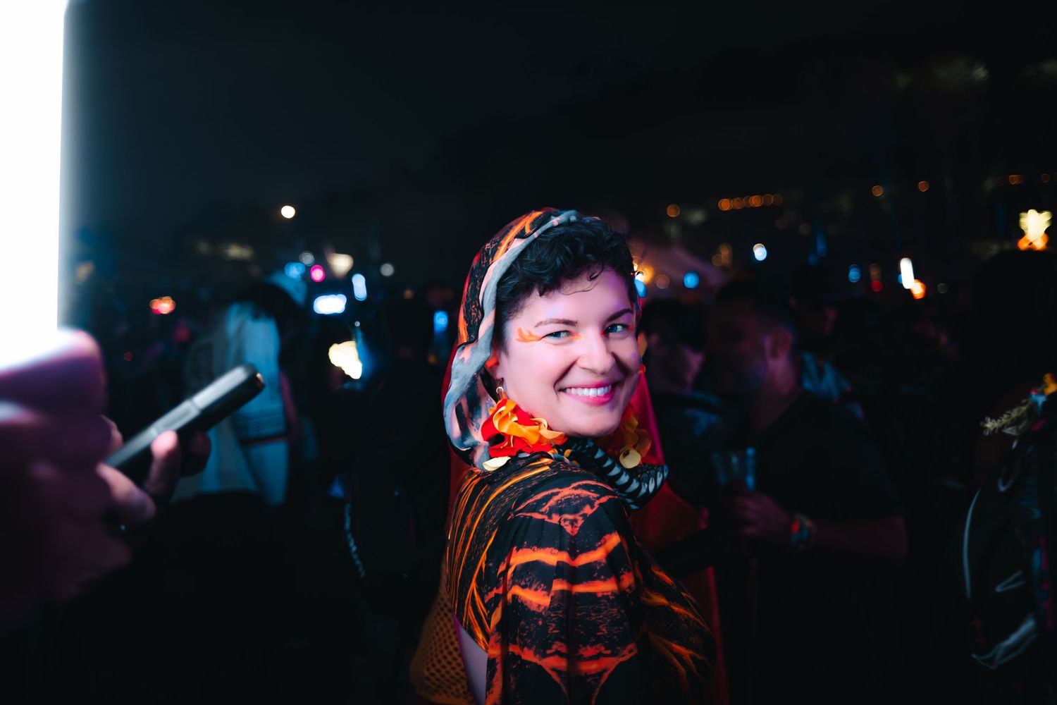 Concert crowd enjoying live music performance in dark venue with colorful stage lighting.