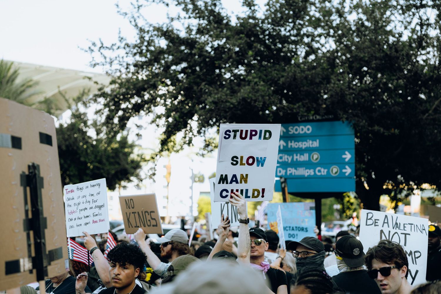 Protest signs and banners held high against a backdrop of trees and buildings.