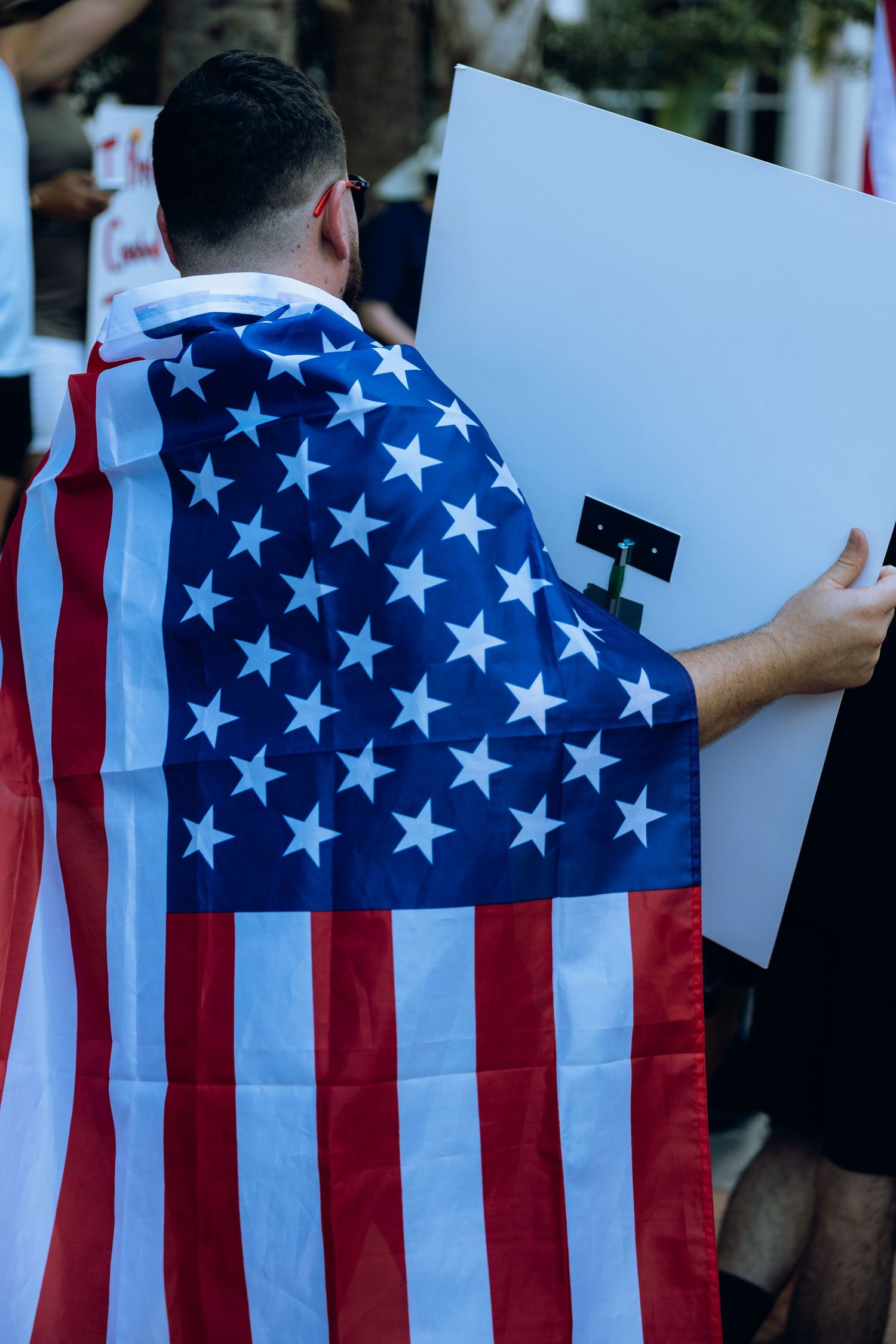 Multiple American flags displayed at a public gathering or protest event in an outdoor setting.
