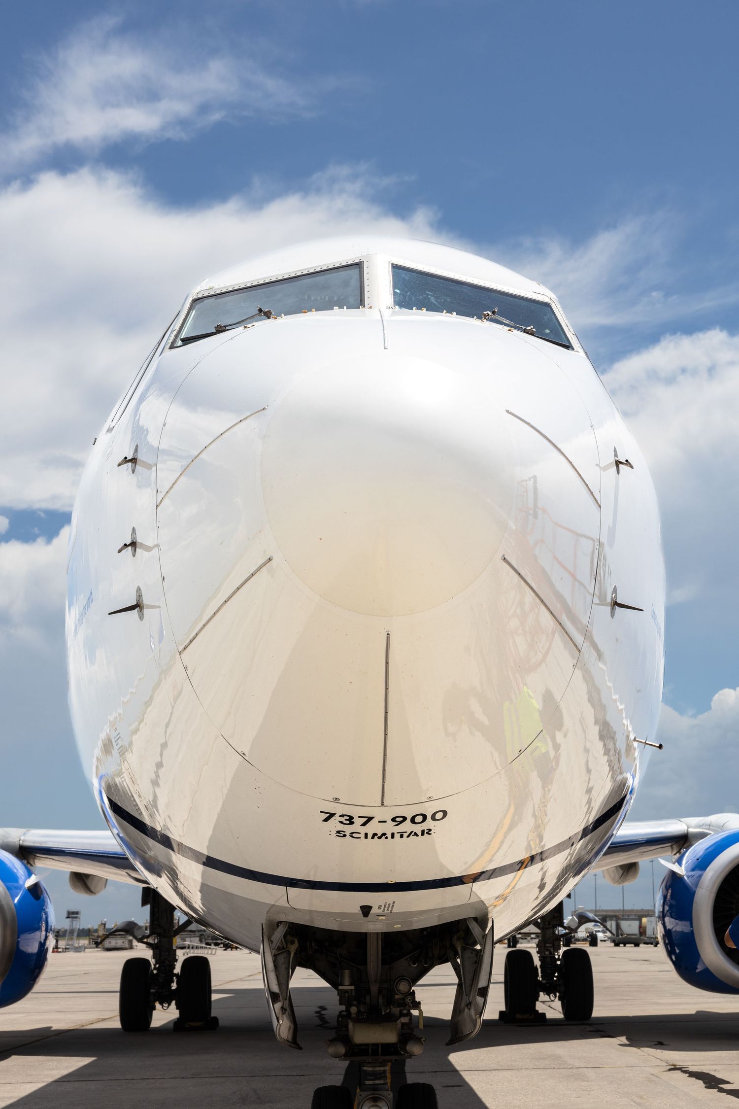 Front view of a Boeing 737-900 Scimitar aircraft on tarmac under blue sky.