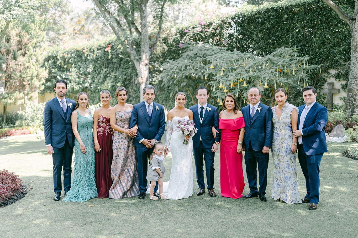 Large wedding family group portrait outdoors with bride, groom, and relatives in colorful formal gowns.