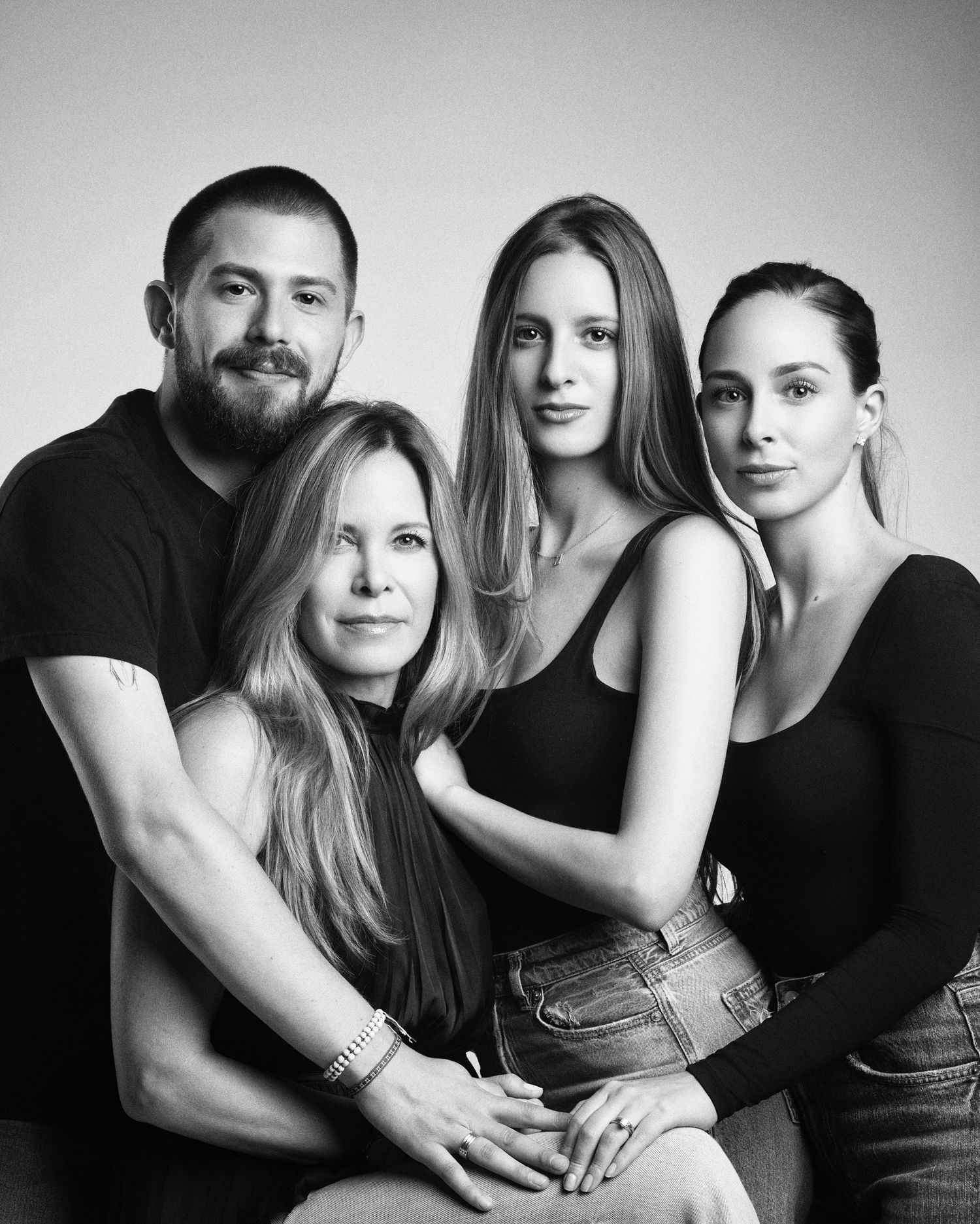 Black and white studio portrait of four family members posing closely together.