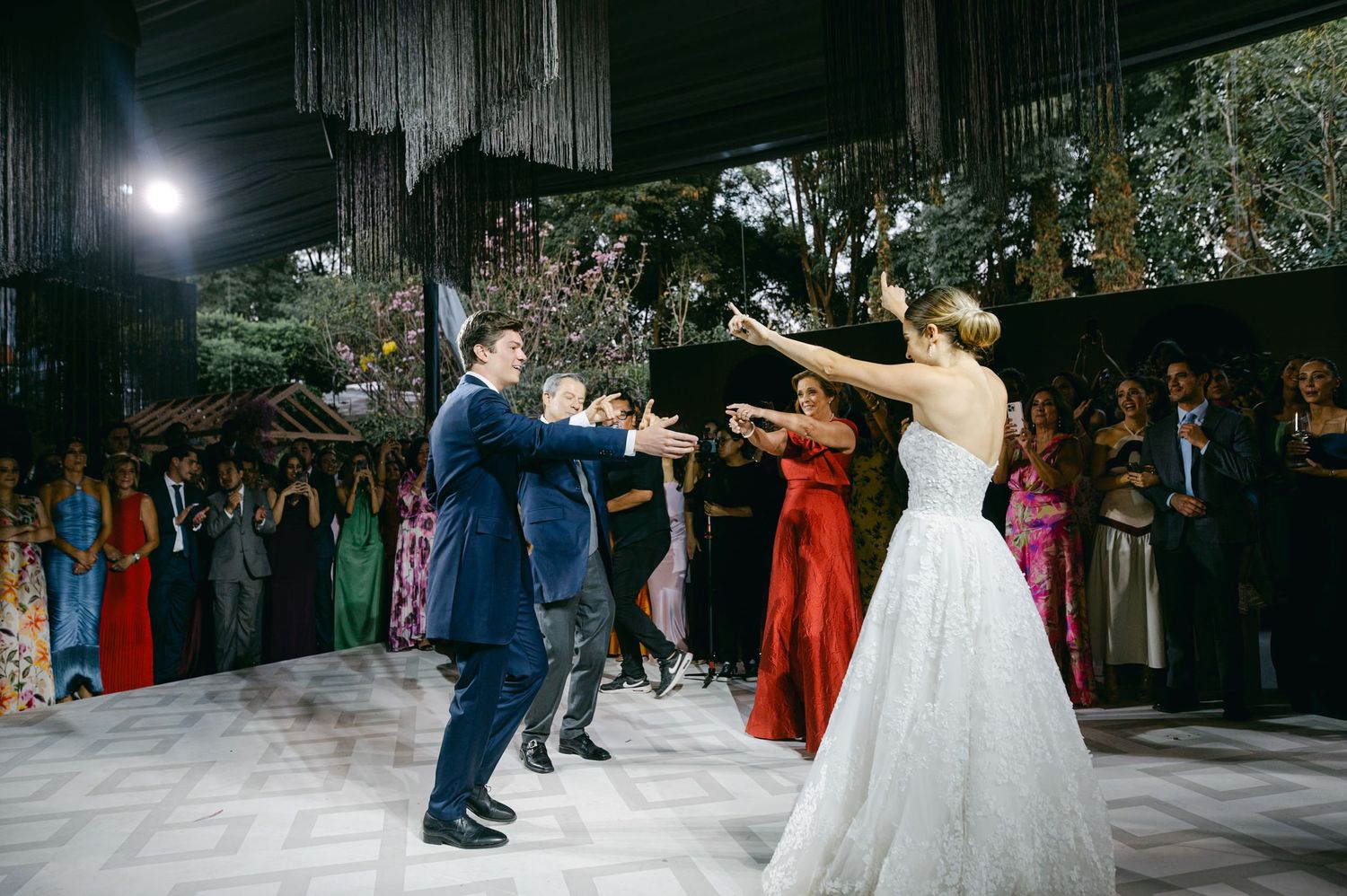 Wedding couple performs energetic dance moves while guests look on at reception.