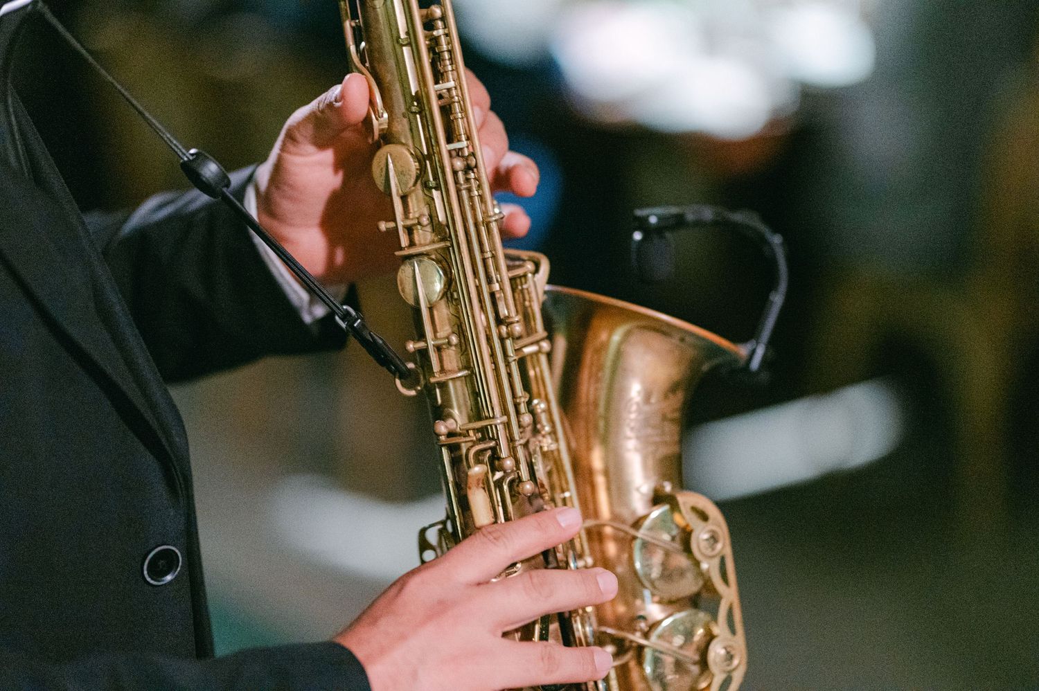 Close-up of a musician's hands playing a brass saxophone at a wedding reception.