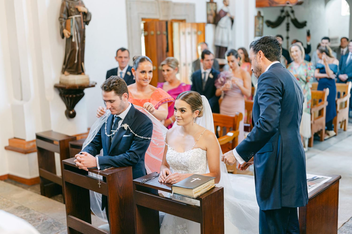 Couple participates in traditional church wedding ceremony surrounded by guests and elegant decor.