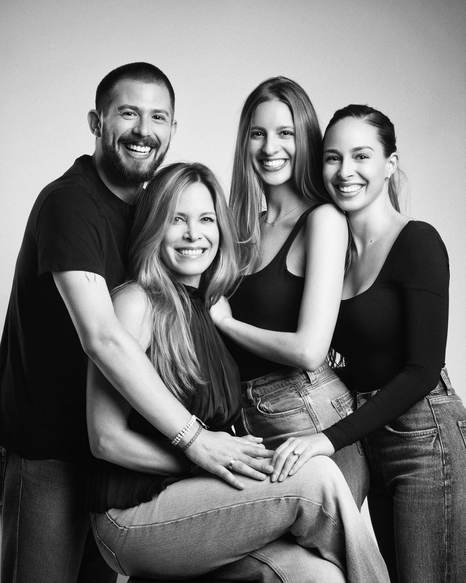 Black and white studio portrait of a happy family of four smiling together.