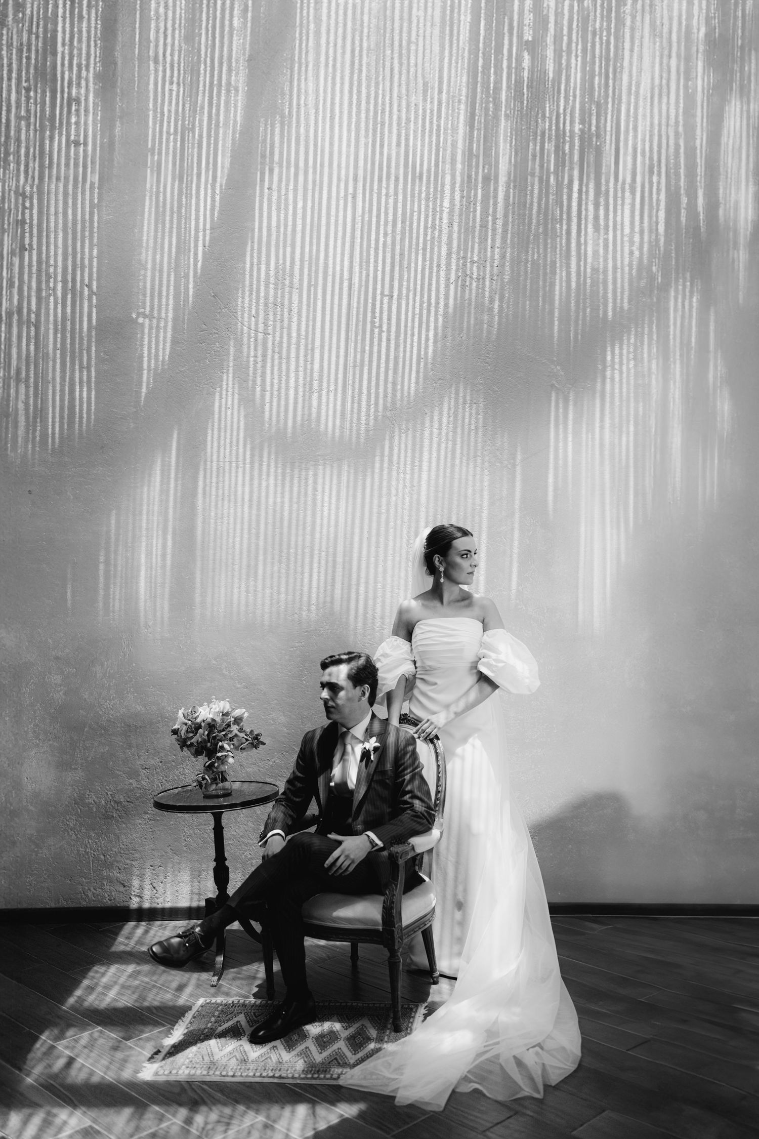 Elegant black and white portrait of bride and groom posing in dramatic light streaked venue.
