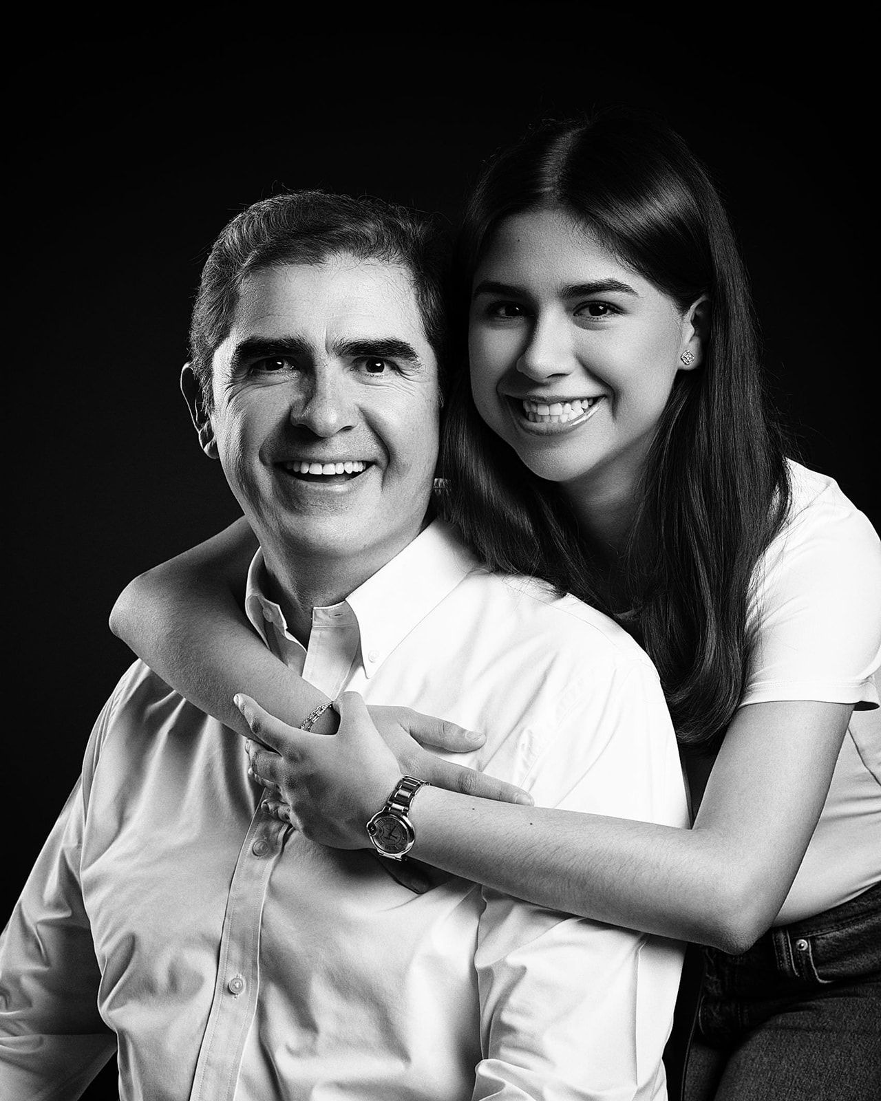 Black and white close-up studio portrait of a smiling man and young woman embracing warmly.