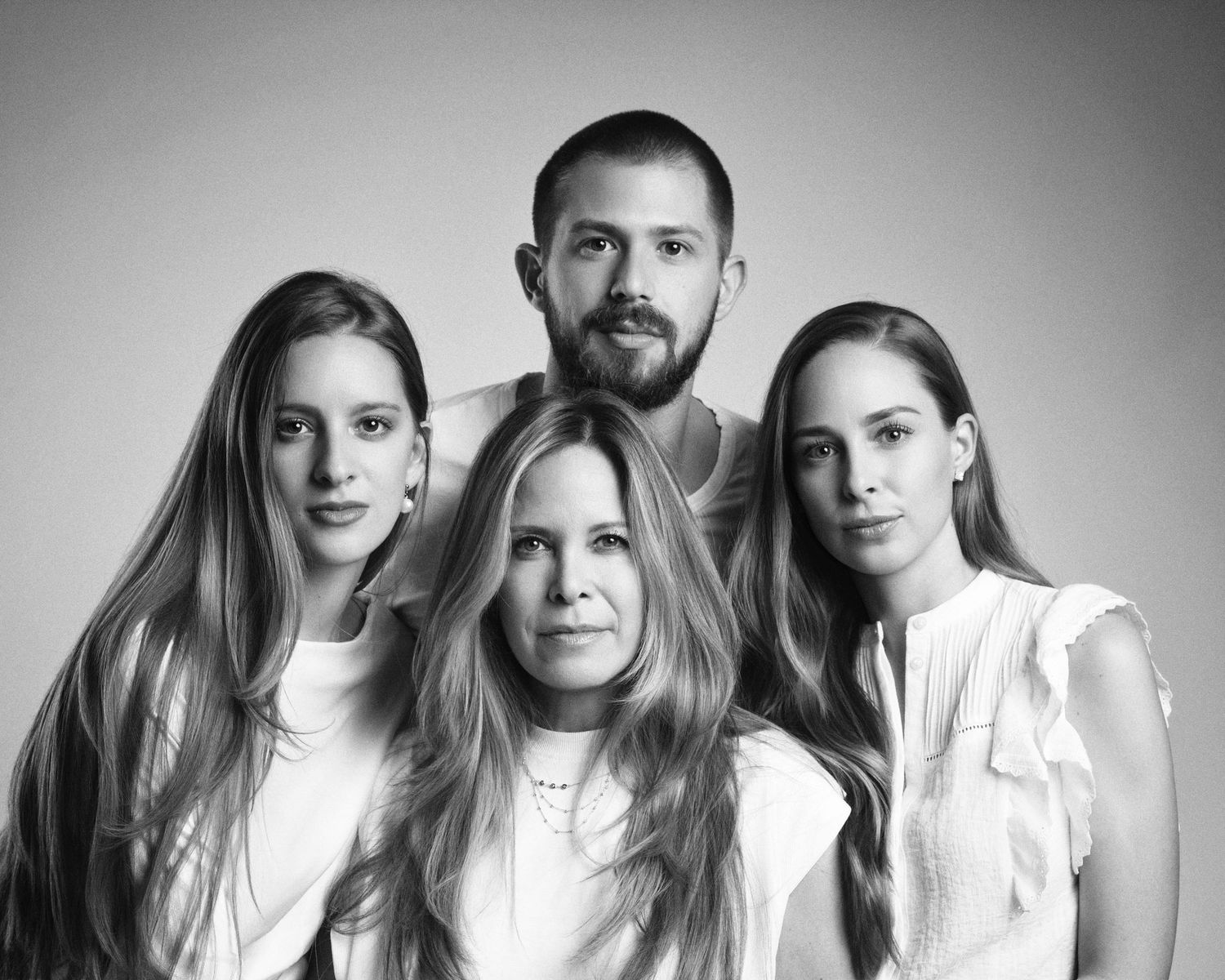 Black and white close-up studio portrait of a family of four, three women and one man posing together.