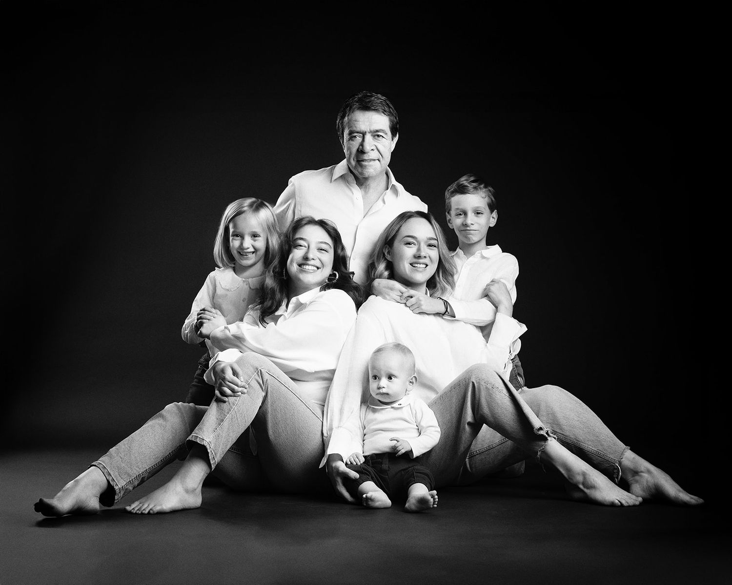 Black and white family portrait of parents with four young children seated together in a studio setting.