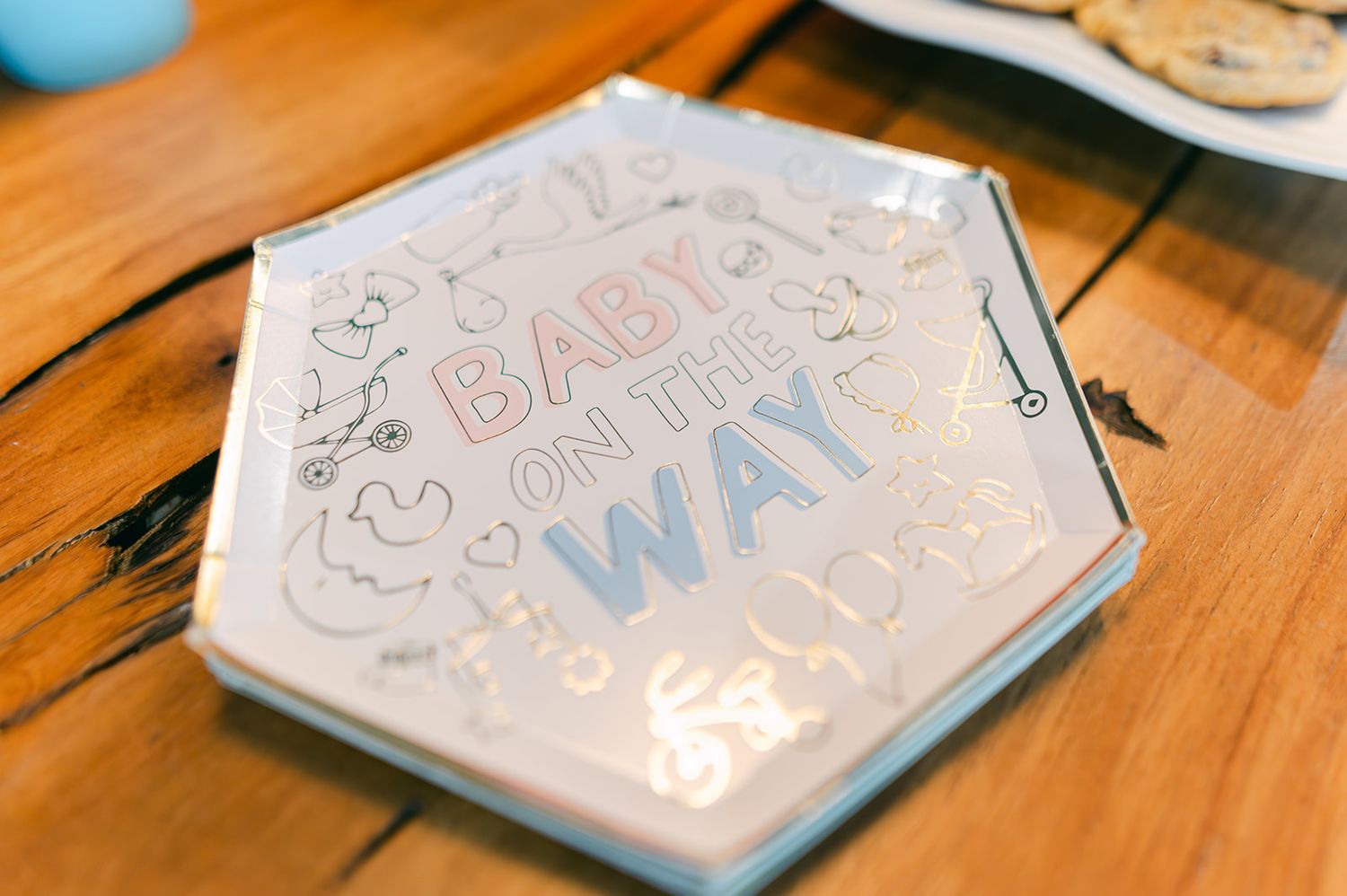 Baby on the Way decorative hexagonal plate on wooden table at gender reveal party.