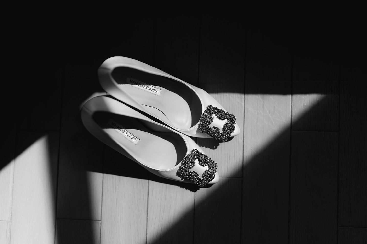 Elegant flat bridal shoes with jeweled buckle detail in black and white photo.