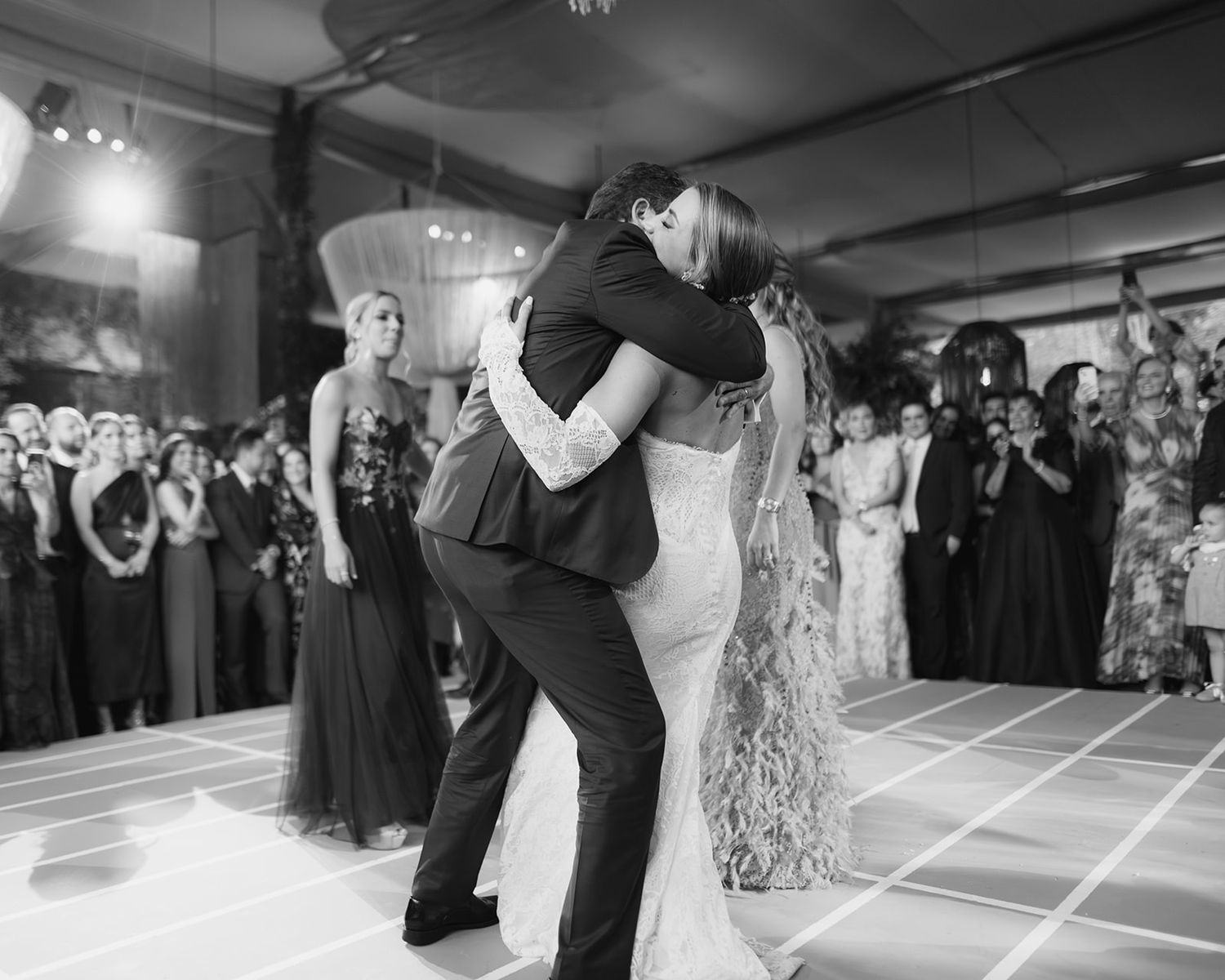 Bride and groom share emotional first dance embrace at elegant black and white wedding reception.