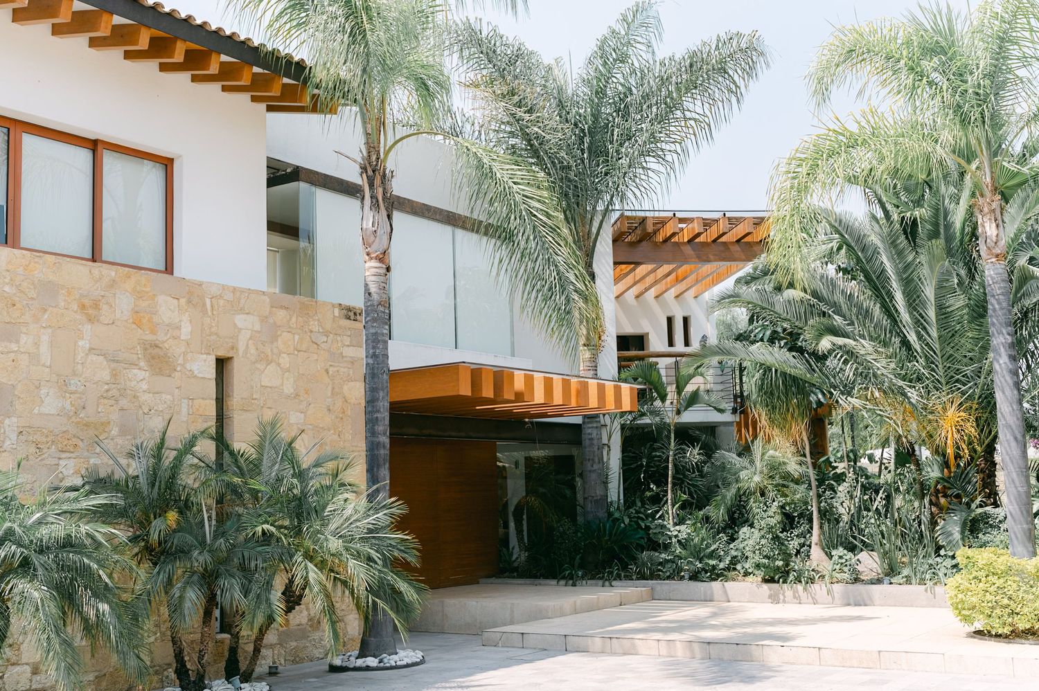 Elegant tropical wedding venue exterior surrounded by lush palm trees and modern glass architecture.