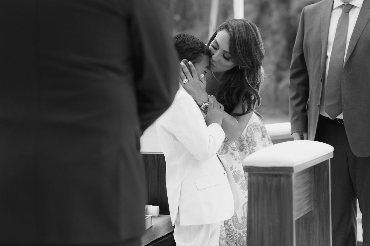 Black and white photo of a couple sharing a kiss at a wedding altar ceremony.