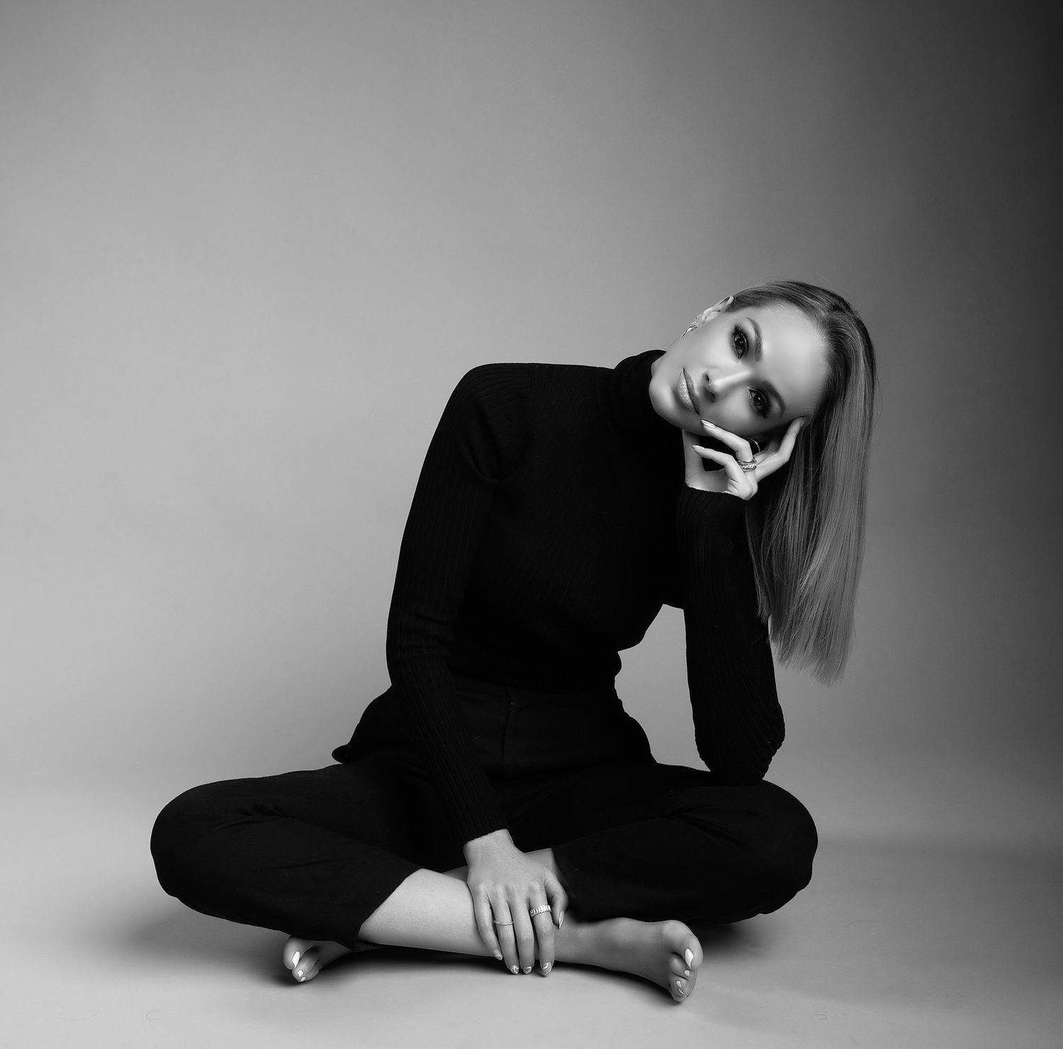 Black and white photo of a woman in black sitting cross-legged on the floor.