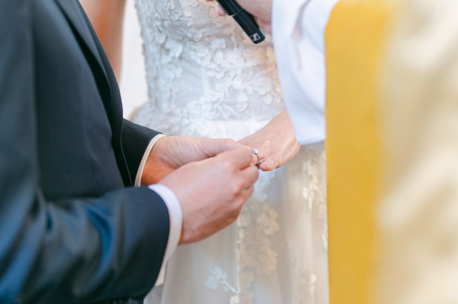 Close-up of wedding ring exchange during traditional church ceremony.