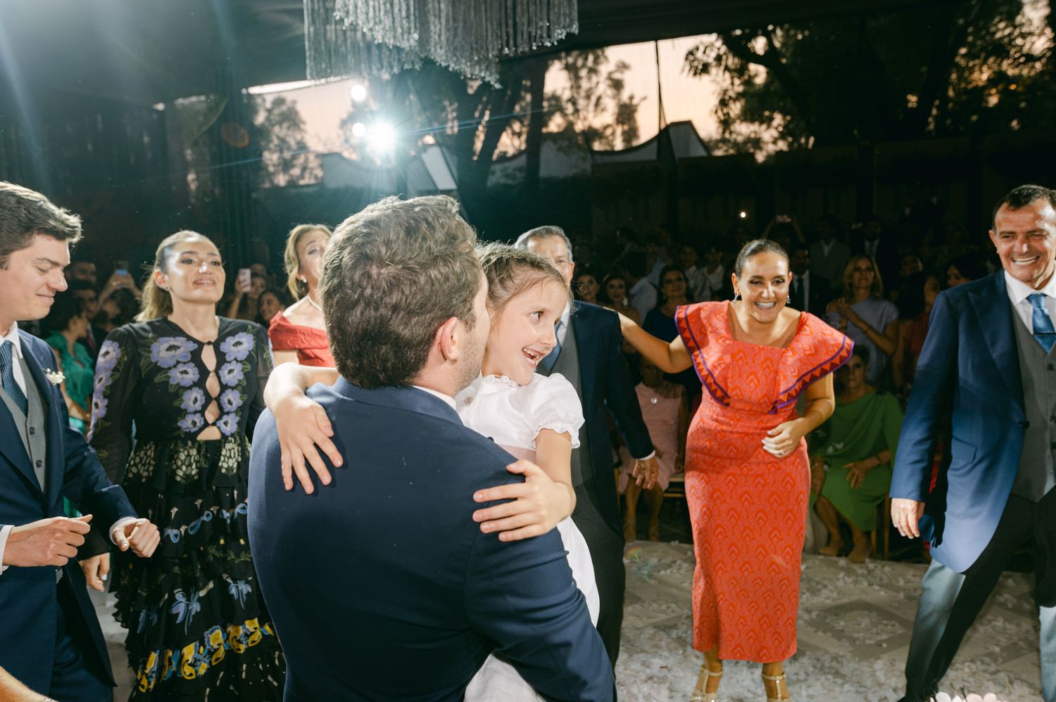 Wedding guests embrace and celebrate on dance floor during reception festivities.