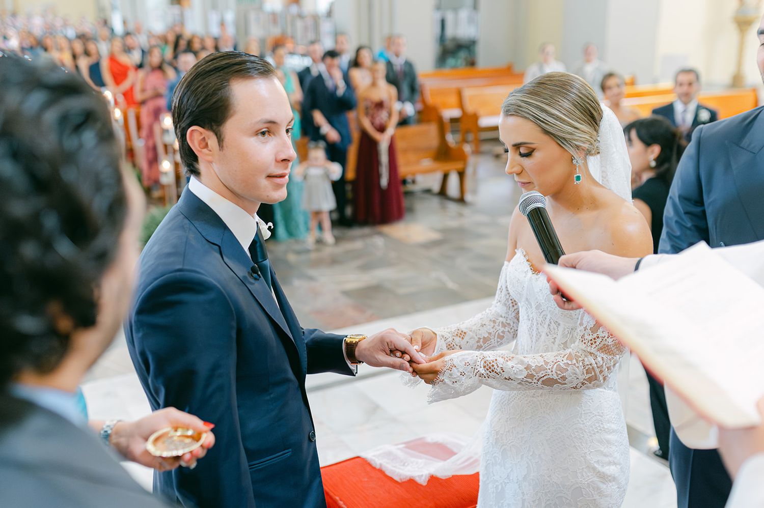 Bride and groom exchange wedding rings at the altar during their church ceremony.