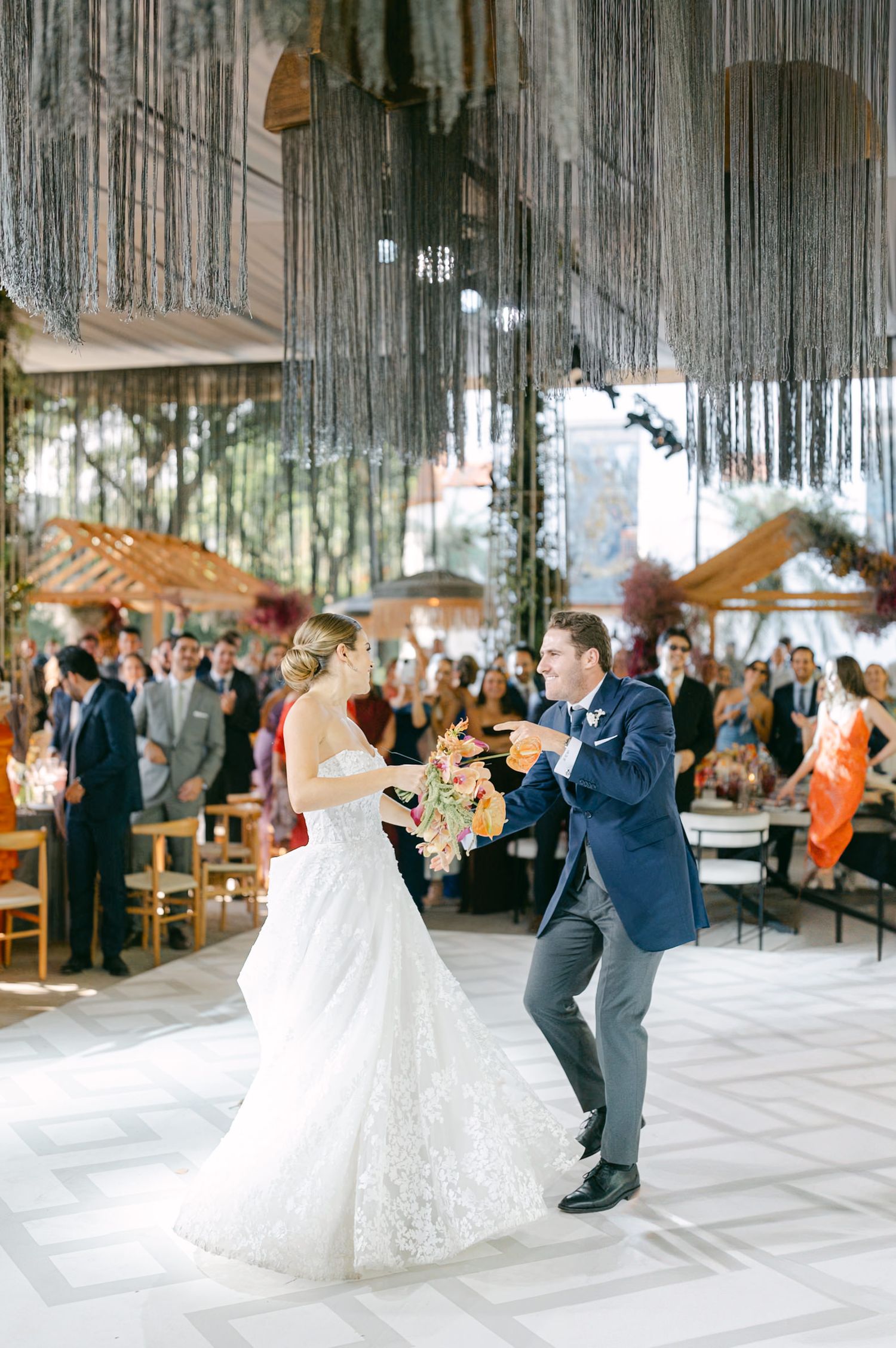 A couple shares a dance moment under dramatic silver hanging decor at their wedding reception.