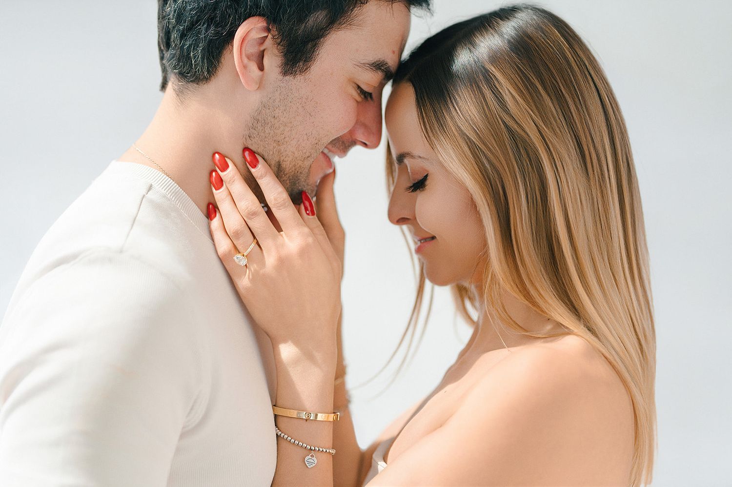 Romantic couple sharing an intimate moment, woman with red nails and bracelet tenderly touching mans face.