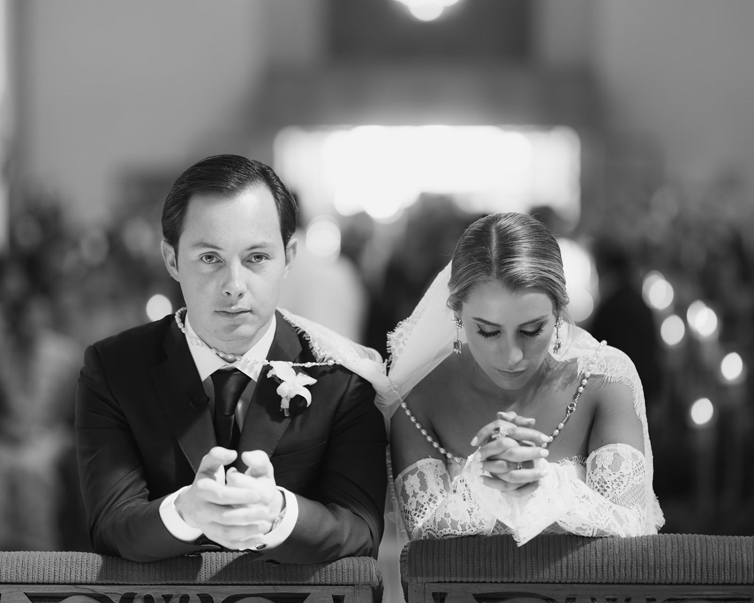 Bride and groom bow heads in prayer together during church wedding ceremony.