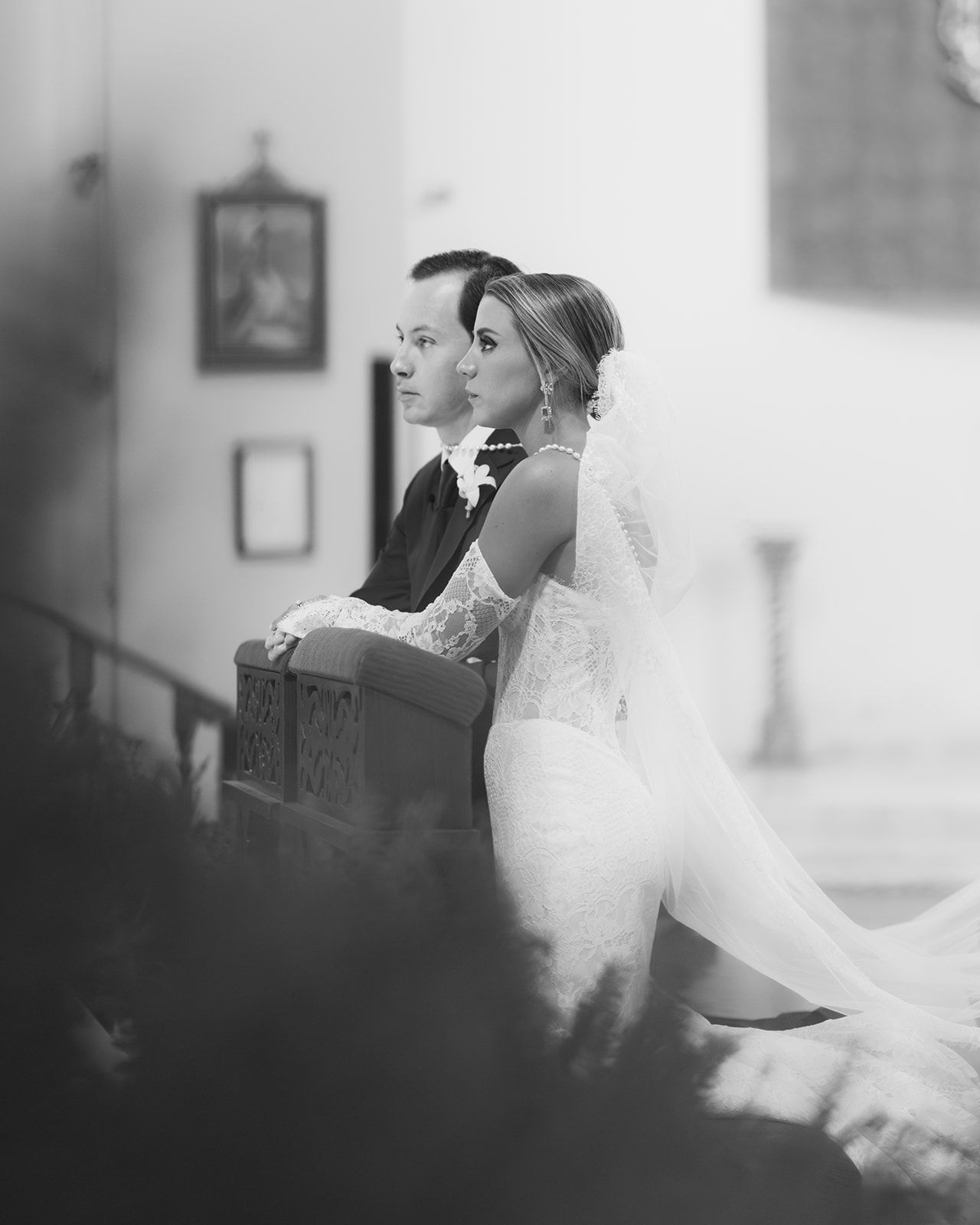 Black and white photo of bride and groom seated together during church wedding ceremony.