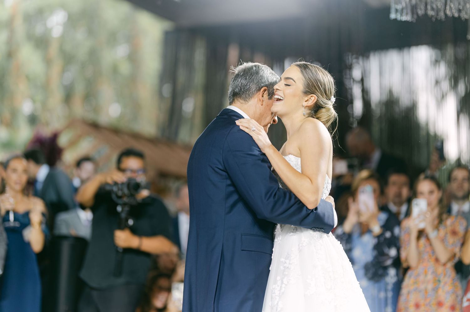 A couple shares an intimate dance moment at their wedding reception surrounded by guests.